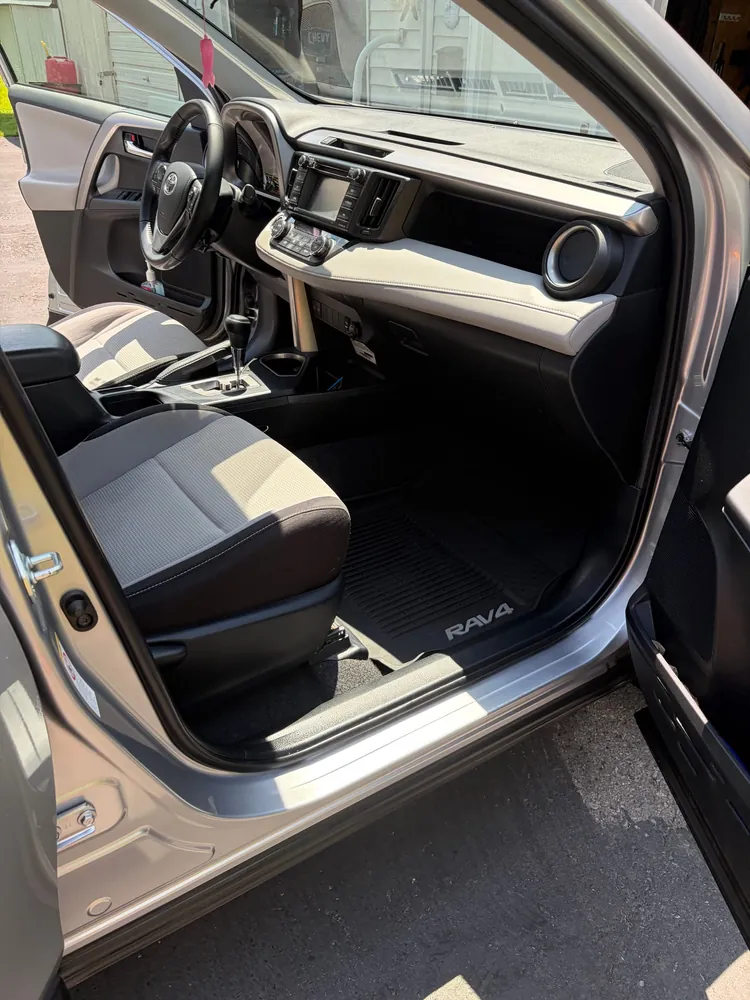 High-end leather car seats thoroughly steam-cleaned and conditioned with a matte OEM satin finish, spotless dashboard and center console, photographed in daylight.